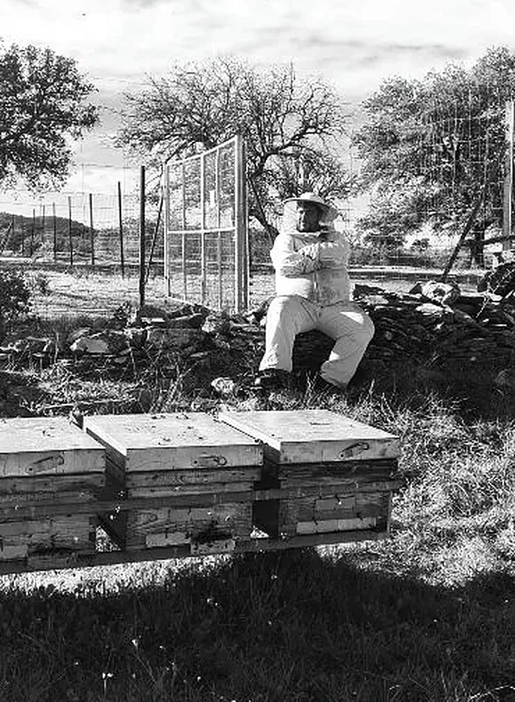 David Salicio sentado junto a sus colmenas, en blanco y negro